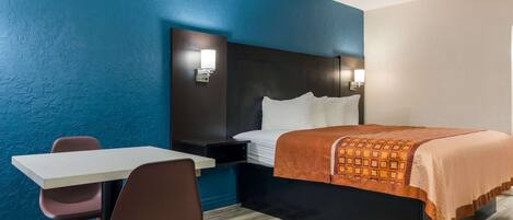 A hotel room with a bed, a desk, and two chairs.