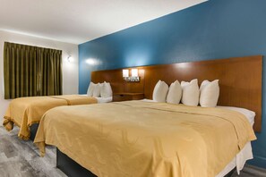A hotel room with two beds, a wooden headboard, and a blue accent wall.