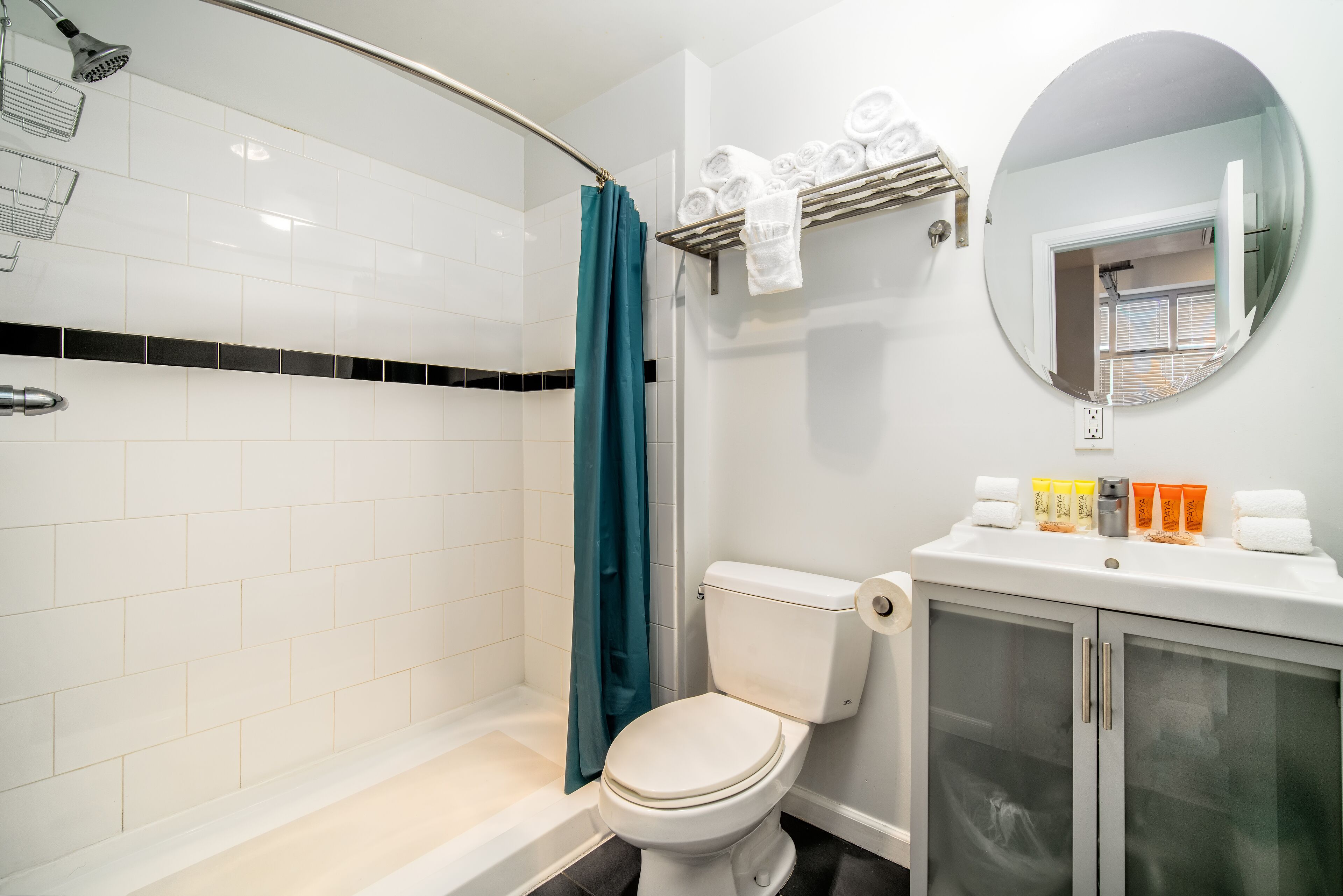 Et badeværelse med brusebad, toilet og håndvask med toiletartikler.