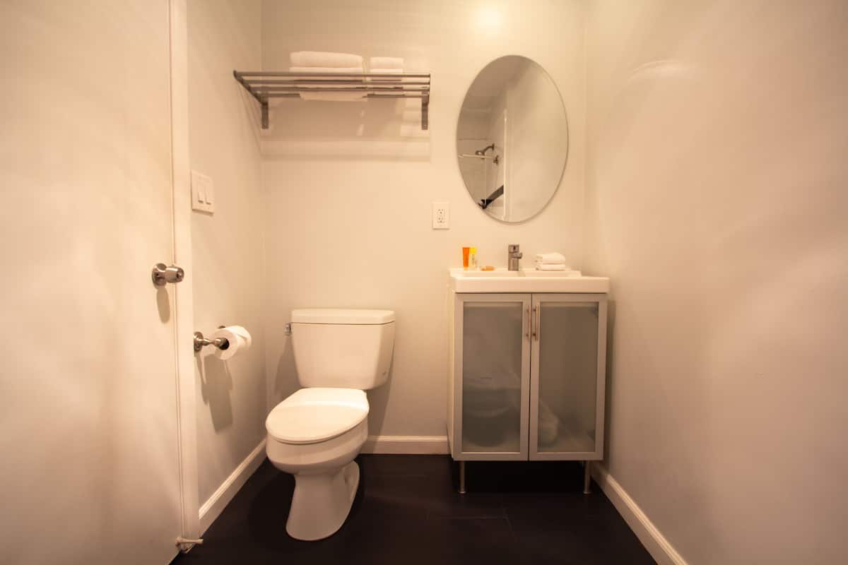 Ein kleines, sauberes Badezimmer mit Toilette, Waschbecken, Spiegel und Handtuchhalter.