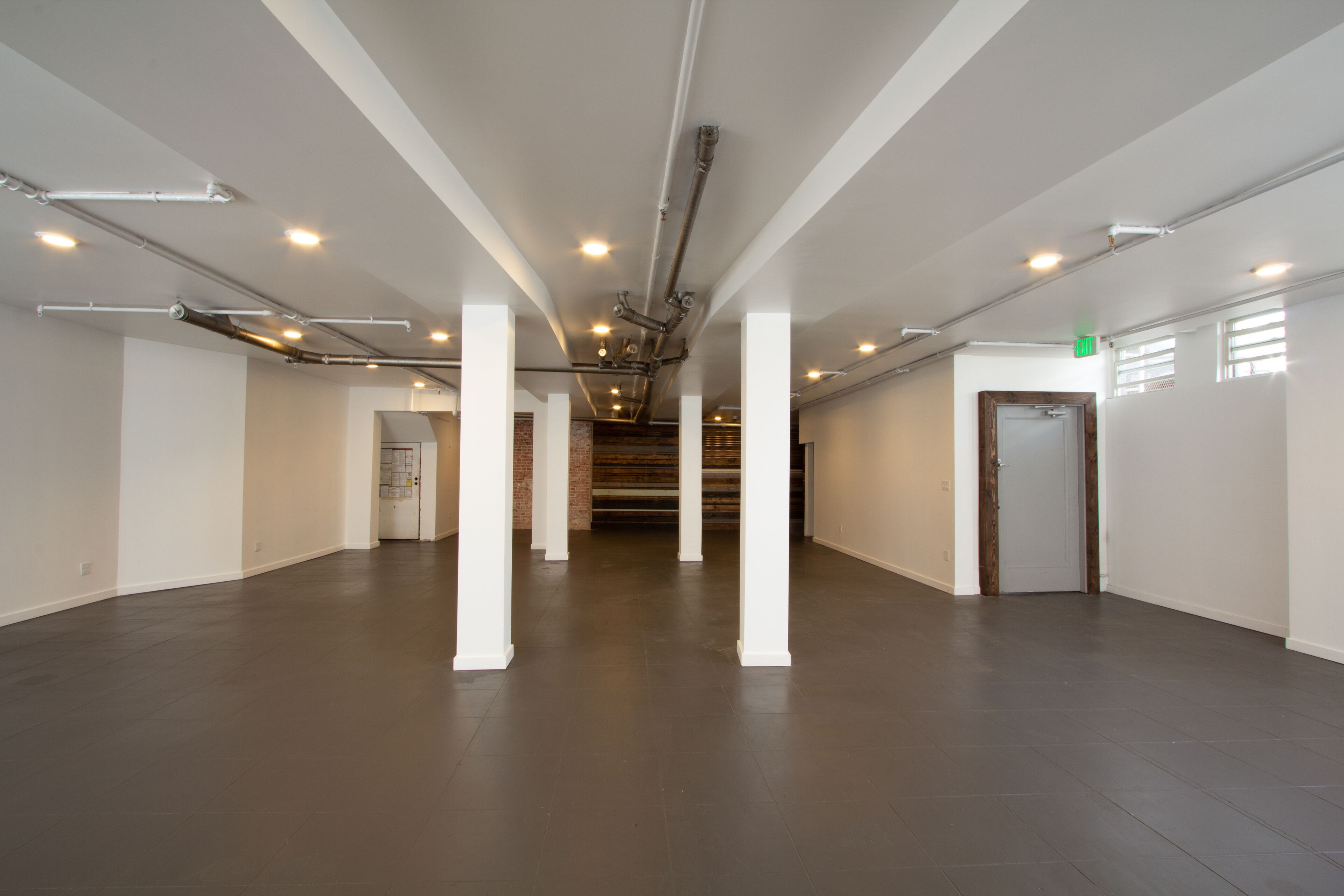 A spacious, modern interior with a high ceiling, exposed ductwork, and a central staircase leading to upper levels.
