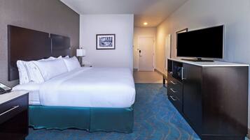 Habitación de hotel con una cama grande, televisión, escritorio con teléfono y puerta que da a otra habitación.