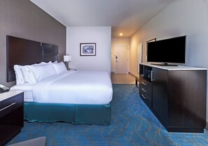Habitación de hotel con una cama grande, televisión, escritorio con teléfono y puerta que da a otra habitación.