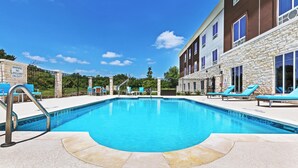 A swimming pool with a lifeguard warning sign, lounge chairs, and a stone building with a pool lift. - Holiday Inn Express & Suites Killeen - Fort Hood Area by IHG (Killeen)