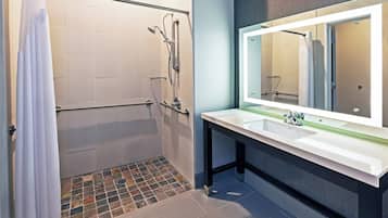 A bathroom with a shower, a sink, and a mirror.