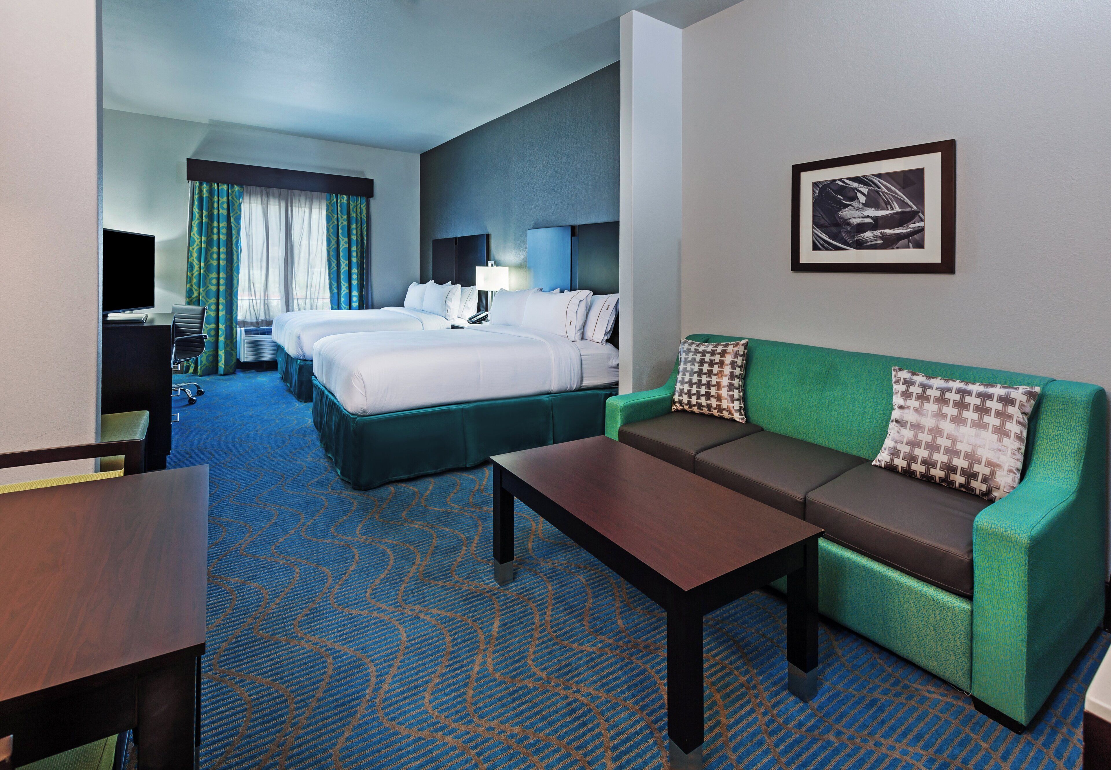 A hotel room with a bed, a sofa, a desk, and a television.