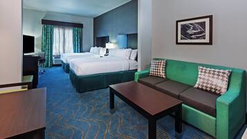 A hotel room with a bed, a sofa, a desk, and a television.