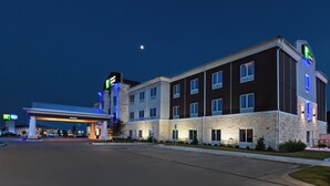 A multi-story hotel with a stone facade, a gas station in the foreground, and a clear night sky. - Holiday Inn Express & Suites Killeen - Fort Hood Area by IHG (Killeen)