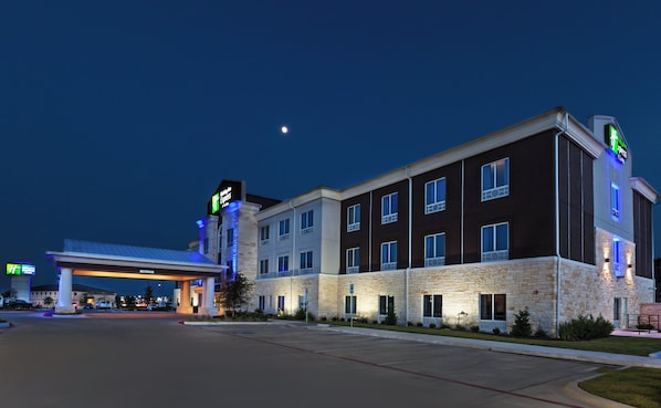 A multi-story hotel with a stone facade, a gas station in the foreground, and a clear night sky. - Holiday Inn Express & Suites Killeen - Fort Hood Area by IHG (Killeen)