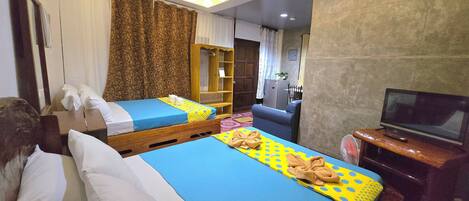 A hotel room with two beds, a TV, and a small desk.