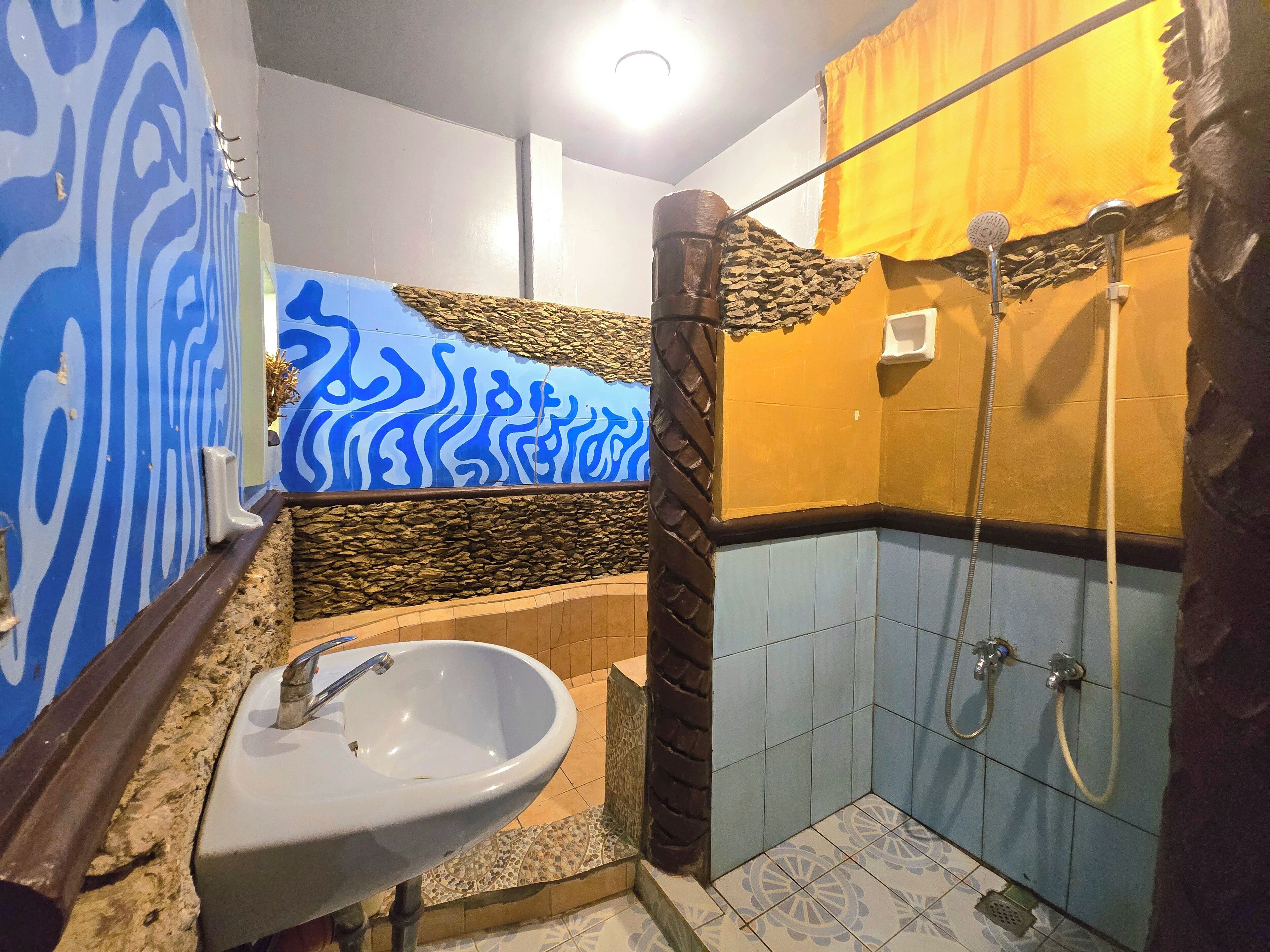 Een badkamer met een wastafel, douche en decoratieve wandtegels.