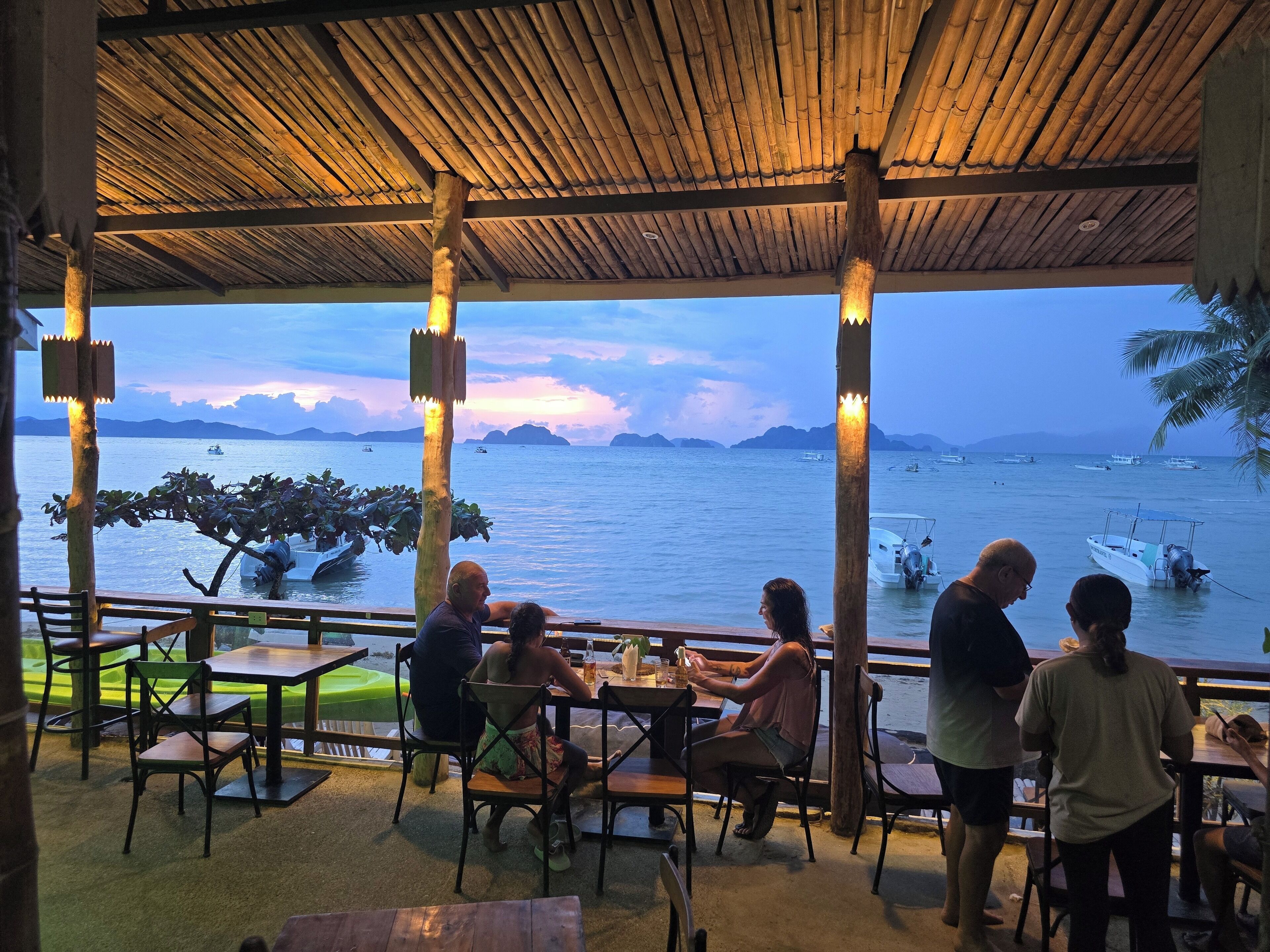 Un espace extérieur aménagé pour prendre les repas, avec vue sur la mer et les bateaux.