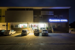A hotel with a modern facade, a parking lot with several cars, and a sign that reads "Chariton Hotel".