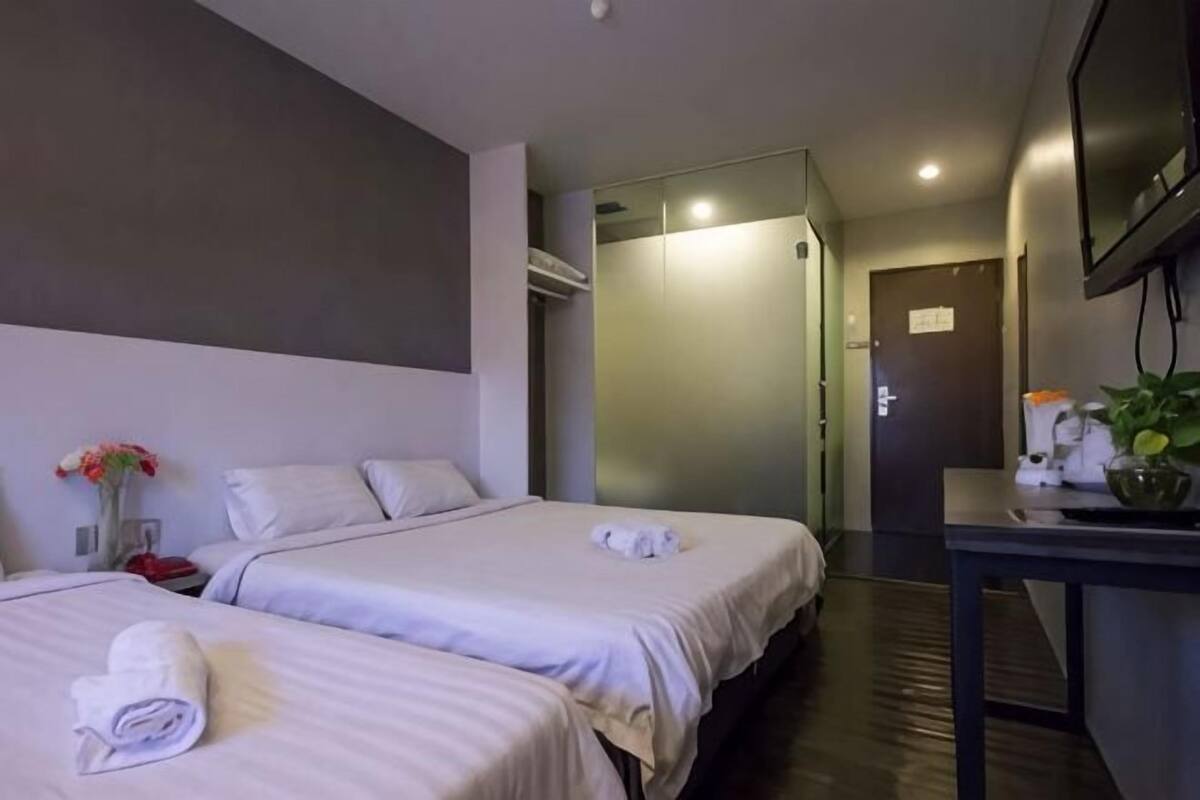 Habitación de hotel con dos camas, televisión, escritorio y planta.