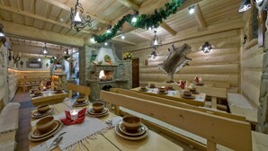 Un interior rústico de madera con paredes de piedra, bancos y mesas dispuestas para comer.
