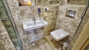 A bathroom with a sink, toilet, and shower area.