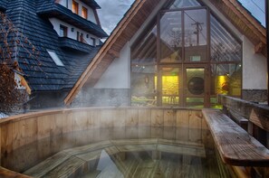 A hot spring area with wooden benches and a stone wall. - Hotel Toporów (Bukowina Tatrzanska)