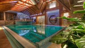 Una piscina interior con techo de madera y paredes de piedra.
