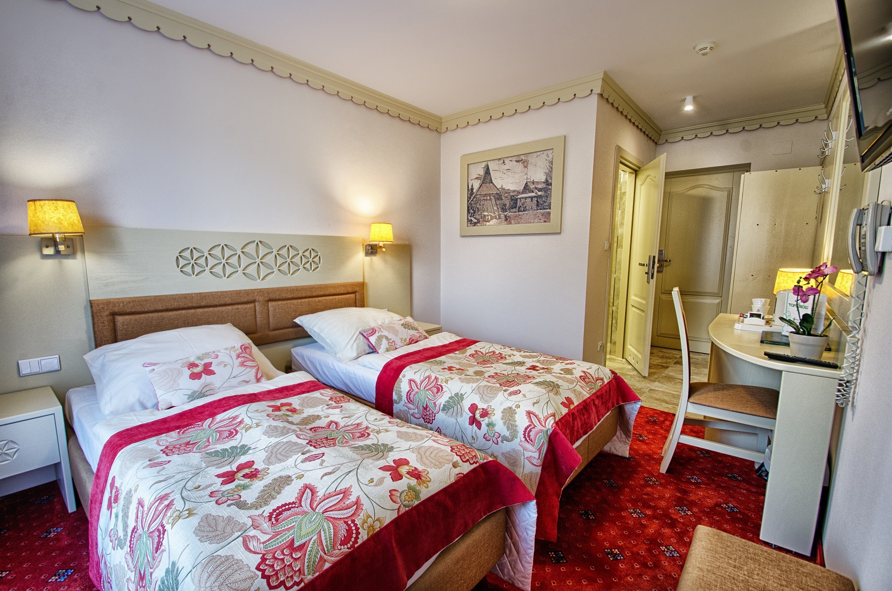 Une chambre d’hôtel avec deux lits, un bureau, une chaise et un miroir.