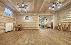 A log cabin interior with wooden walls, a wooden floor, a dining area with chairs, and a chandelier. - Willa U Jadzi (Zakopane)