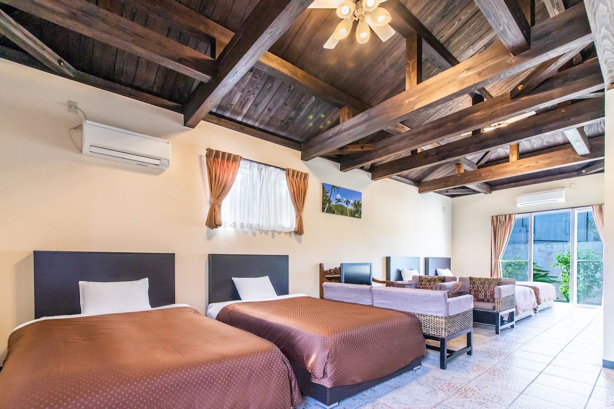A hotel room with two beds, a desk, and a large window.