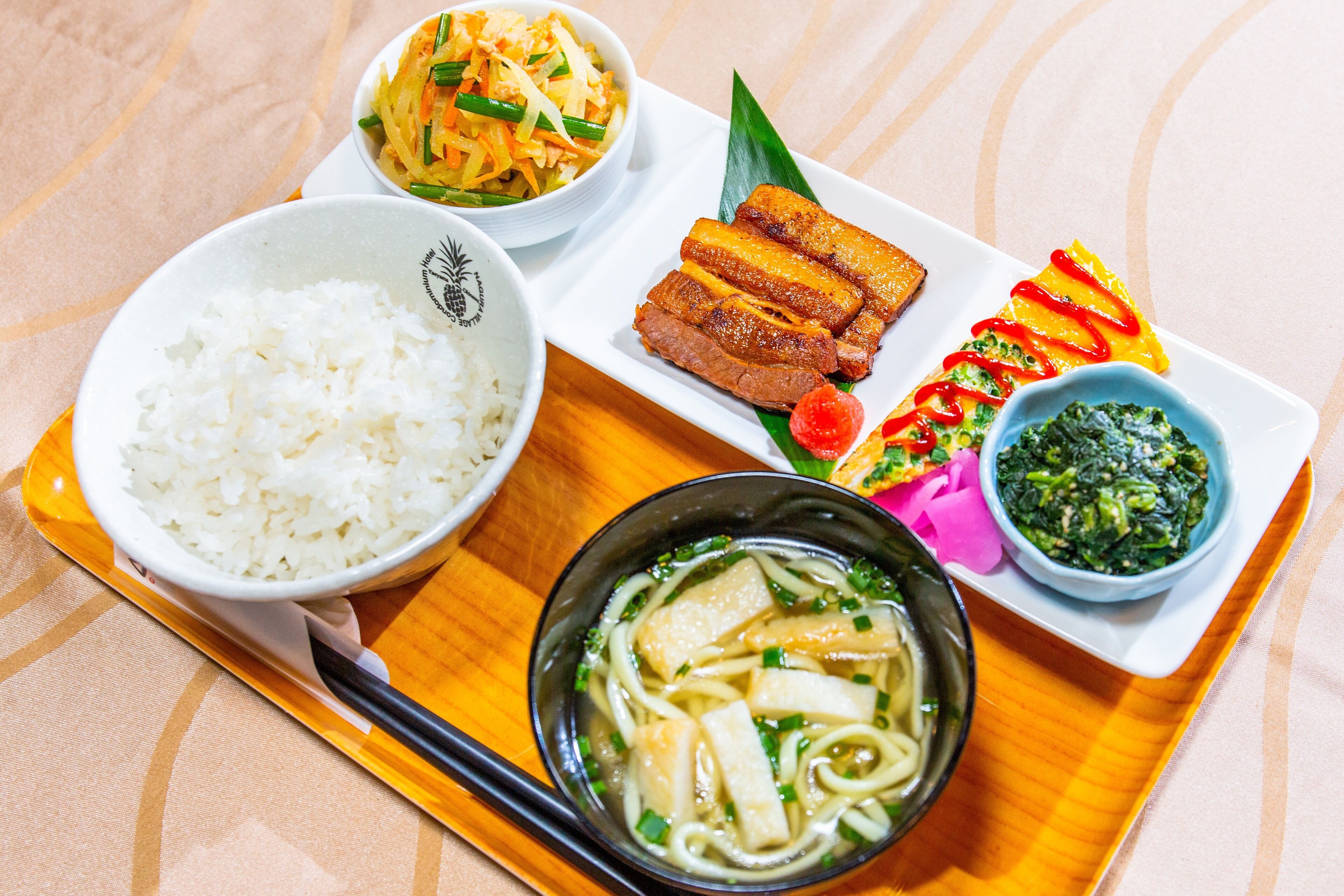 A tray with various dishes including rice, noodles, and a bowl of soup.