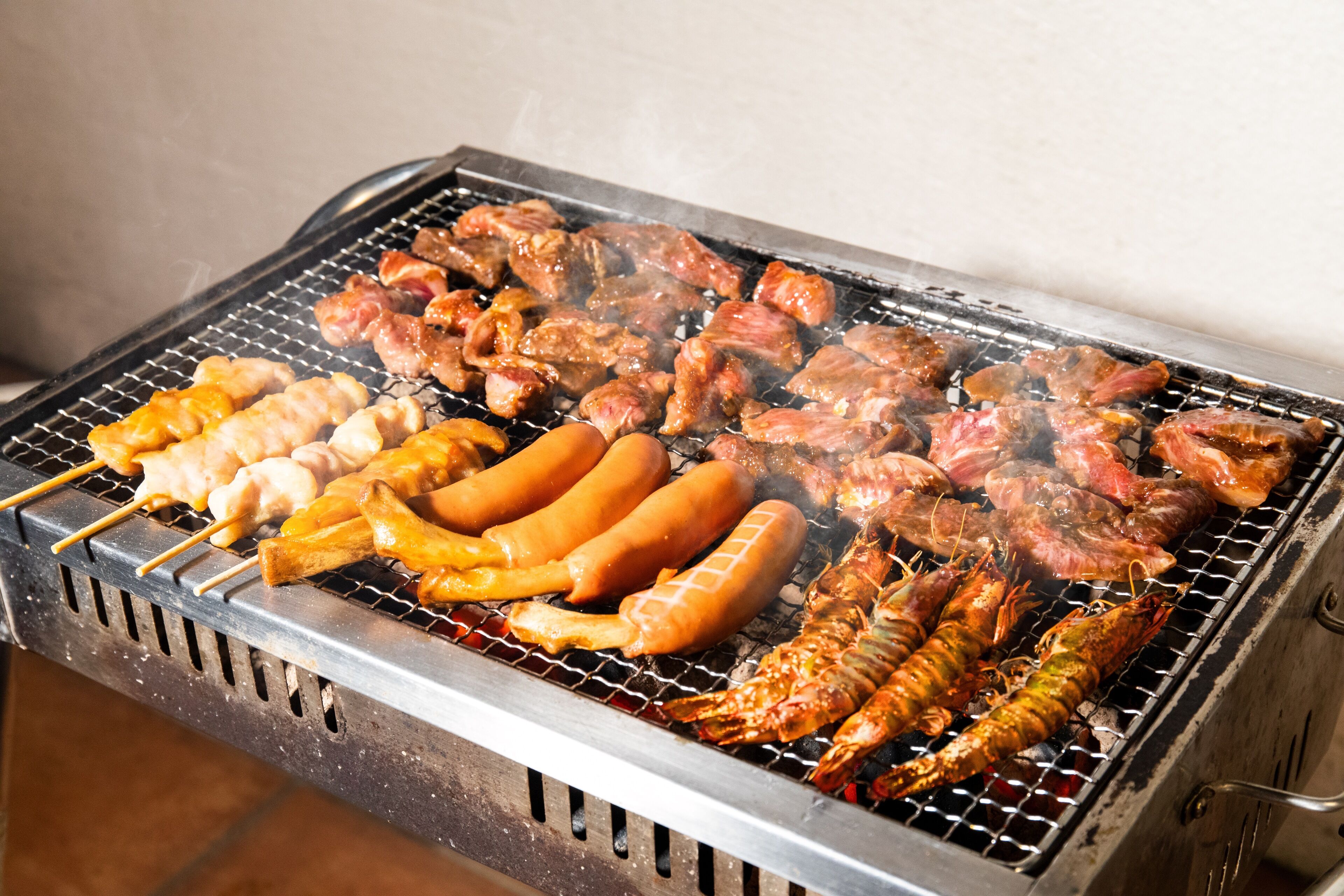 A variety of meats and seafood being grilled on a barbecue.