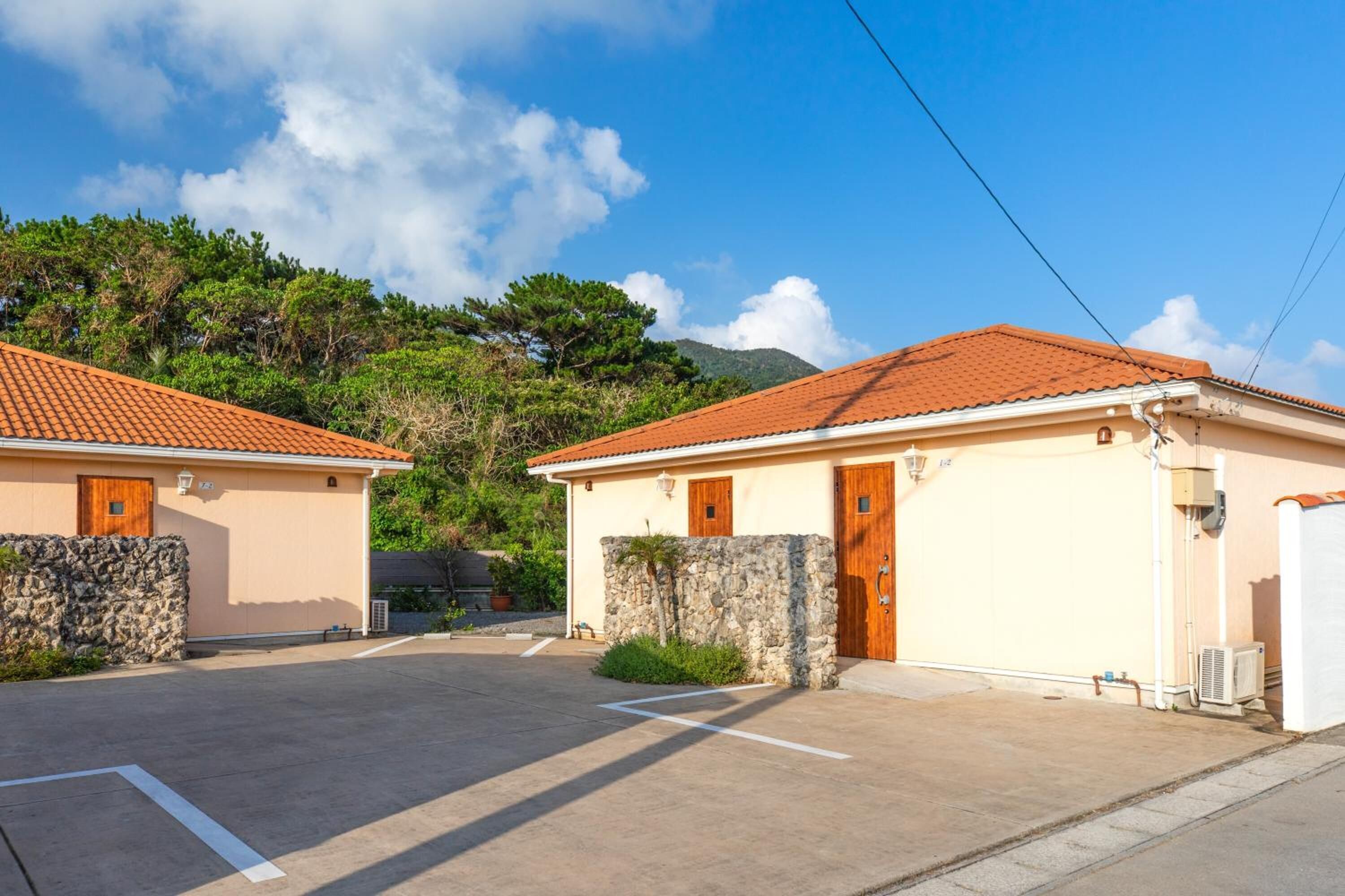 A residential area with two houses, each with a tiled roof and a stone wall.
