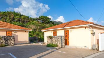 A residential area with two houses, each with a tiled roof and a stone wall.