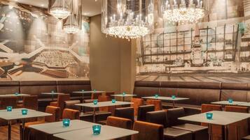 A restaurant with booths, tables, and hanging crystal chandeliers.