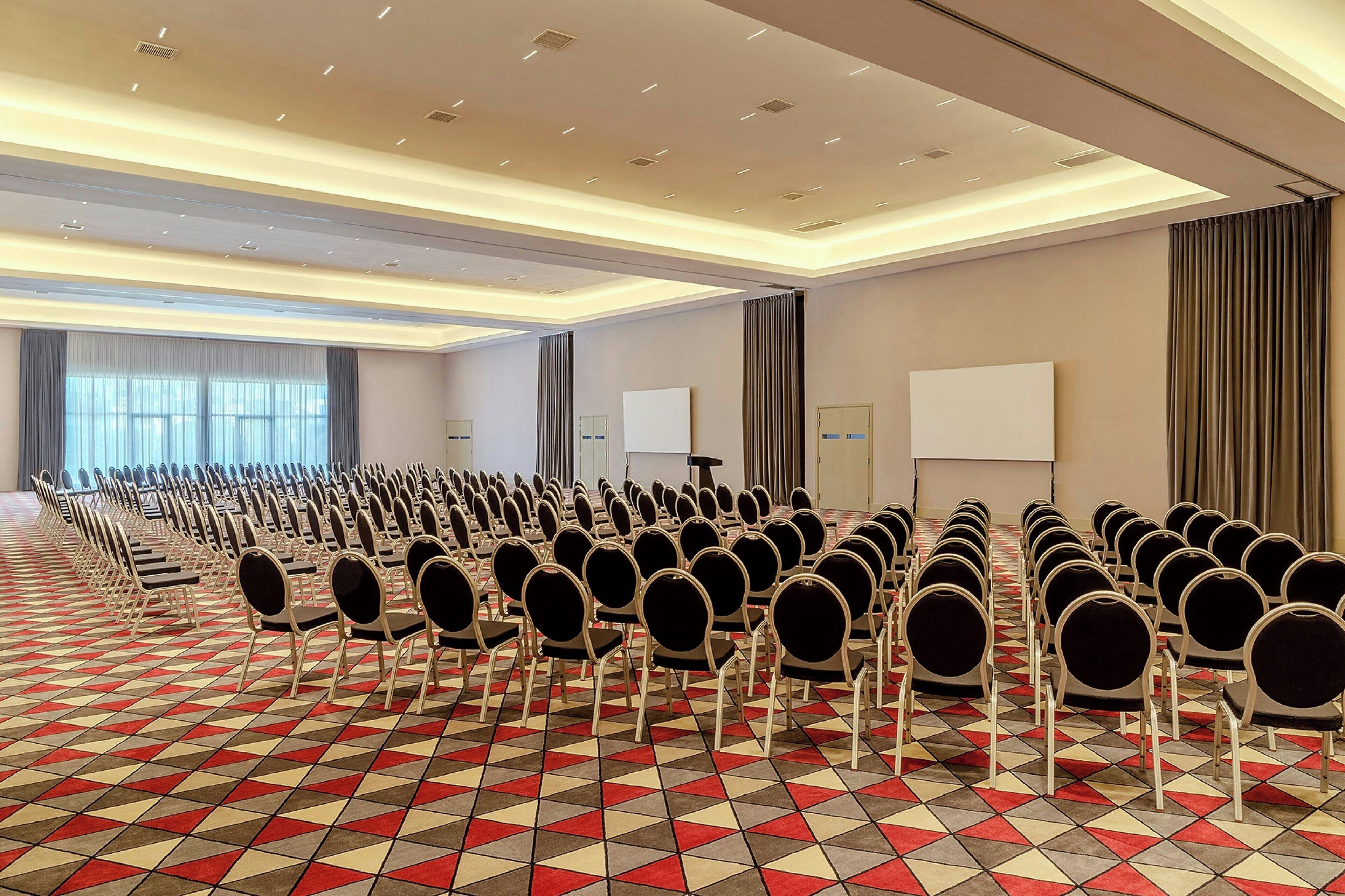 A conference room with rows of chairs, a projector screen, and a whiteboard.