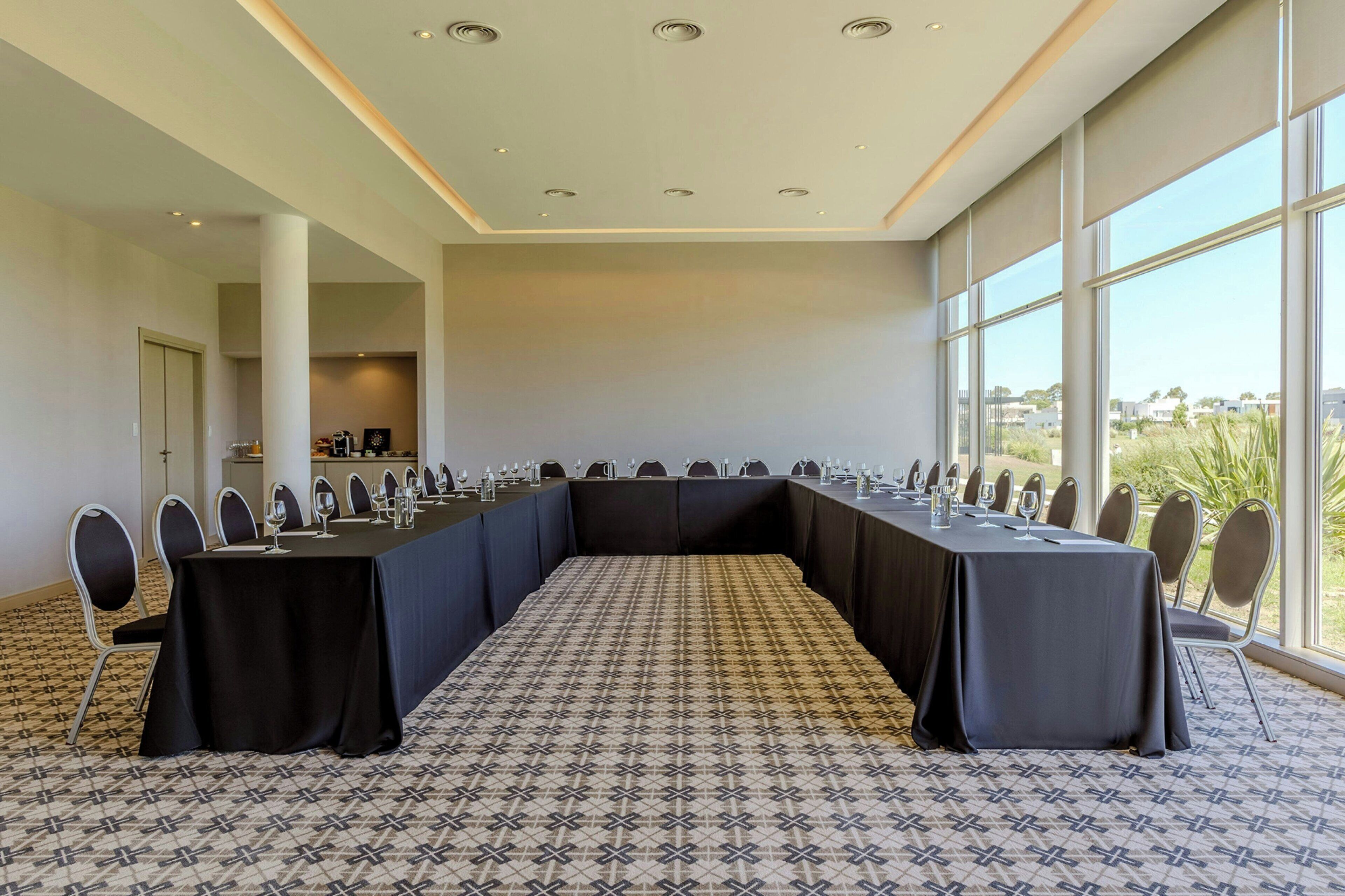 A conference room with a long table, chairs, and a patterned carpet.