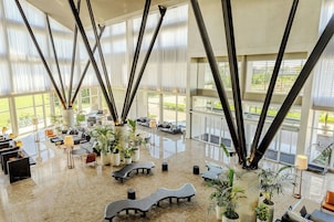 Um hall amplo com pé direito alto, grandes janelas e mobiliário moderno.