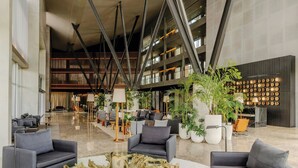 Een ruime lobby met modern meubilair, een grote houten salontafel en potplanten.