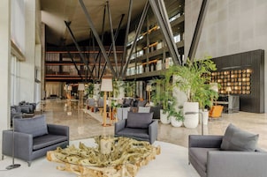 Um hall amplo com móveis modernos, uma grande mesa de centro de madeira e plantas em vasos.