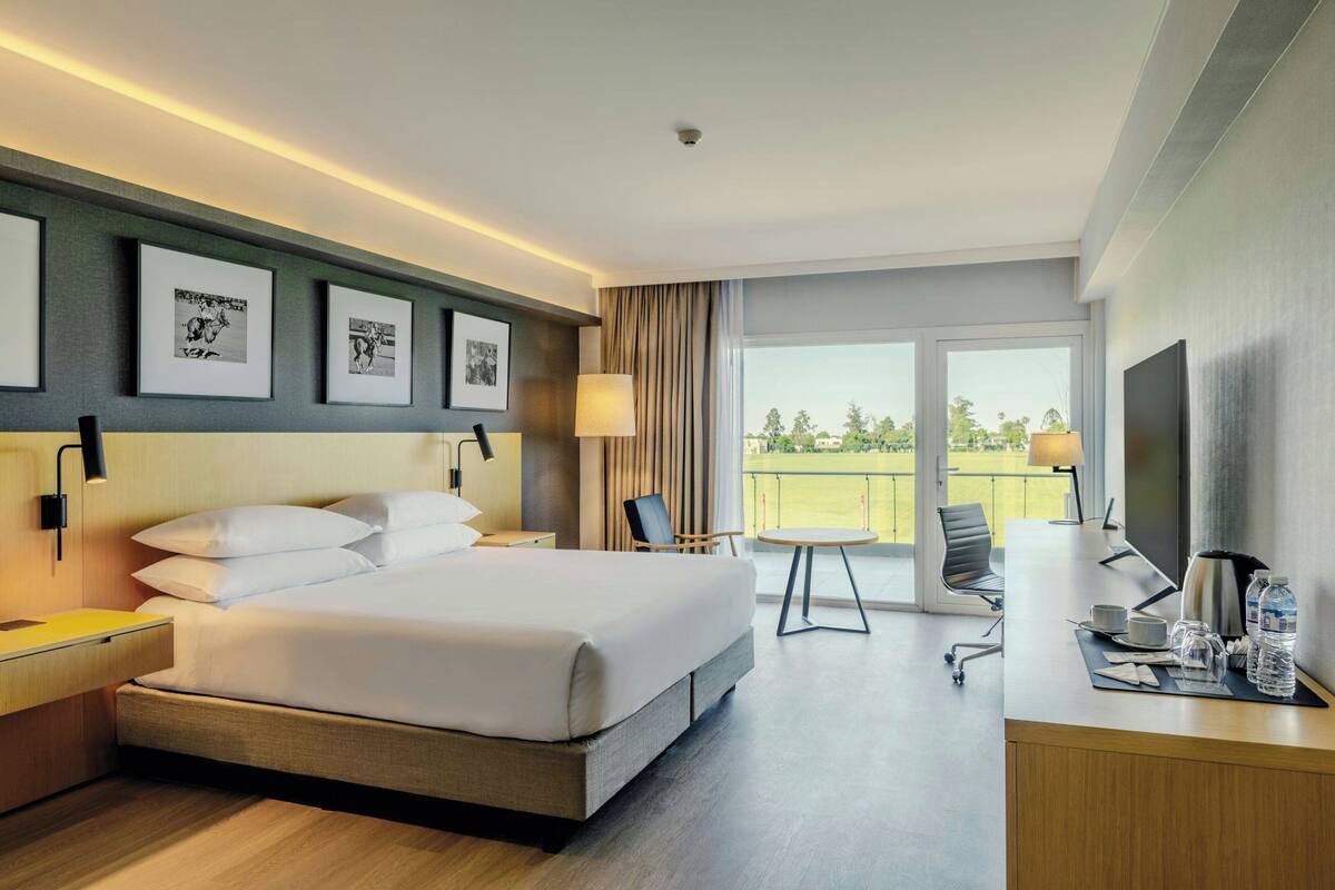 A hotel room with a bed, desk, chair, and large window.