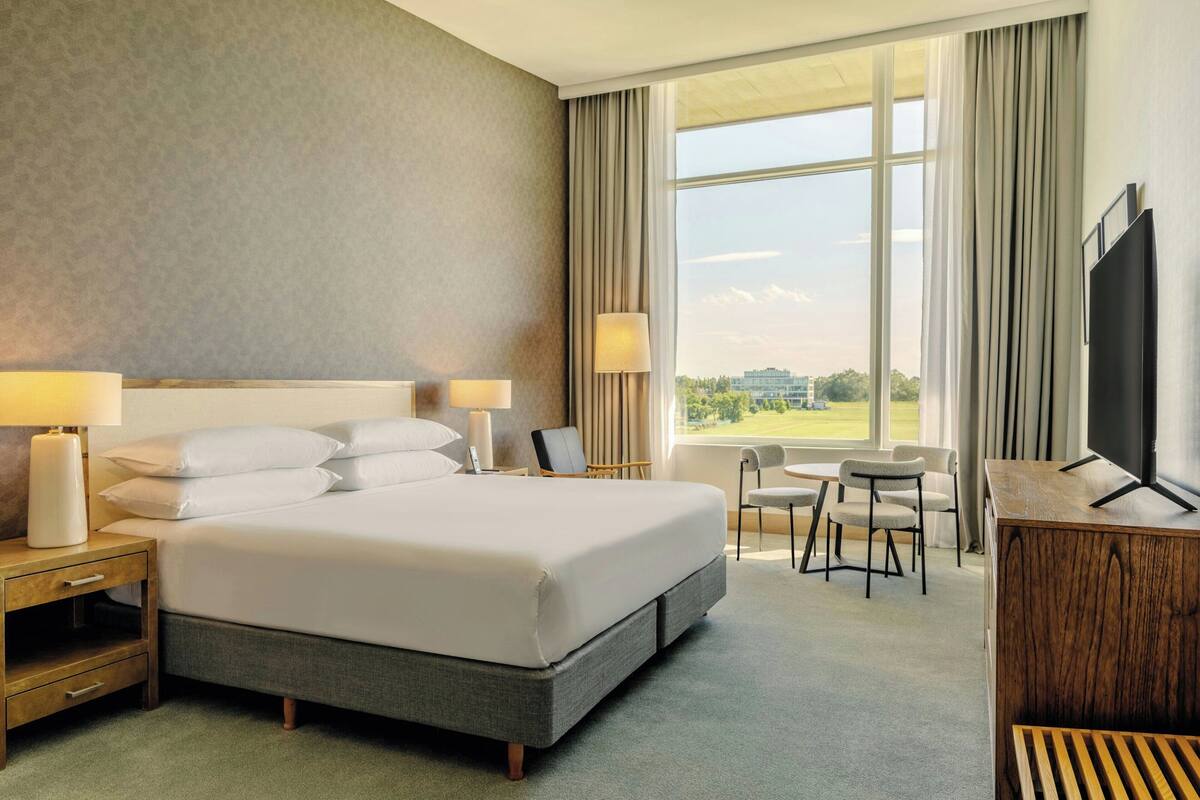 A hotel room with a large bed, two bedside tables with lamps, a desk, and a chair.