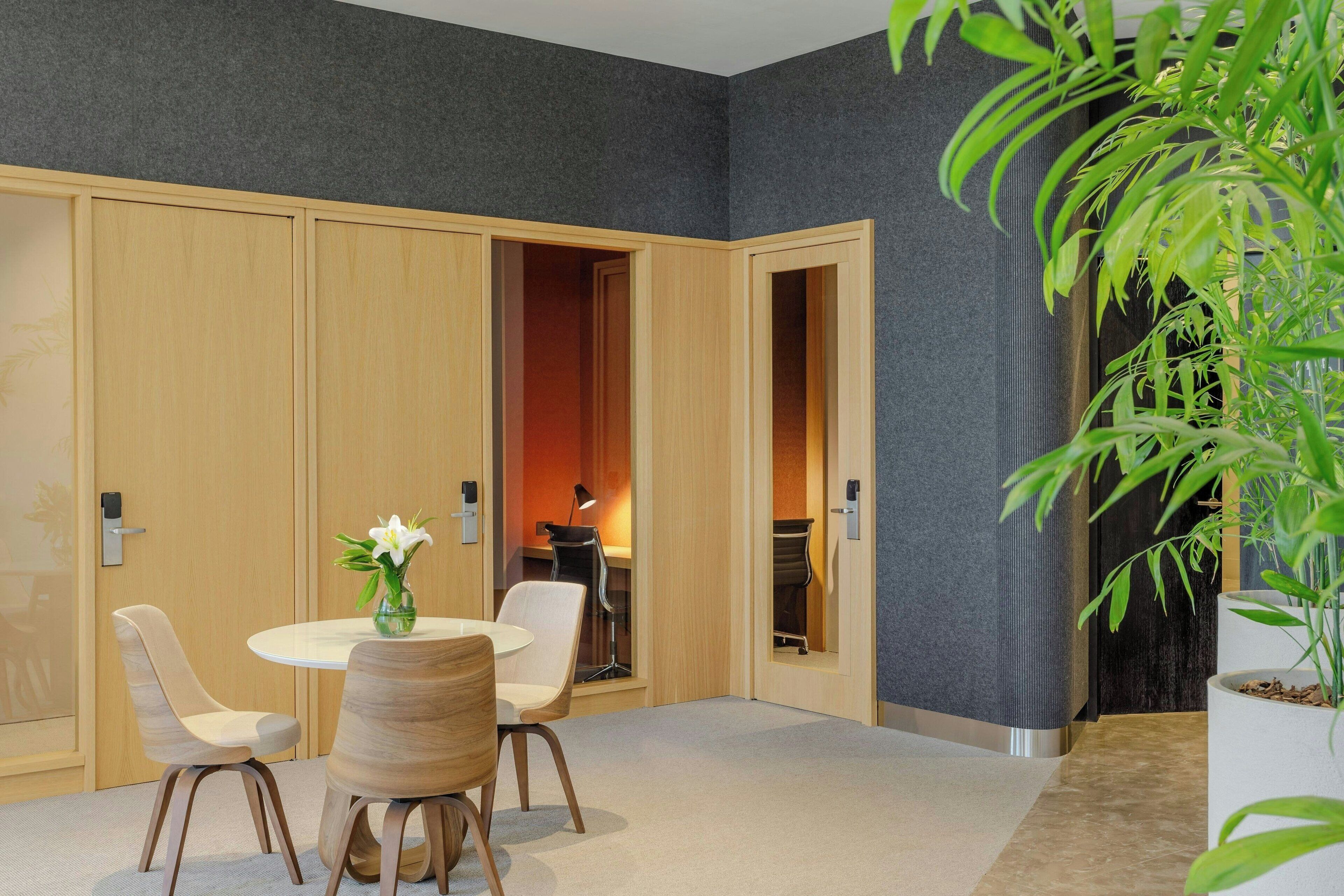 A modern room with a round table, two chairs, a potted plant, and a large wardrobe.
