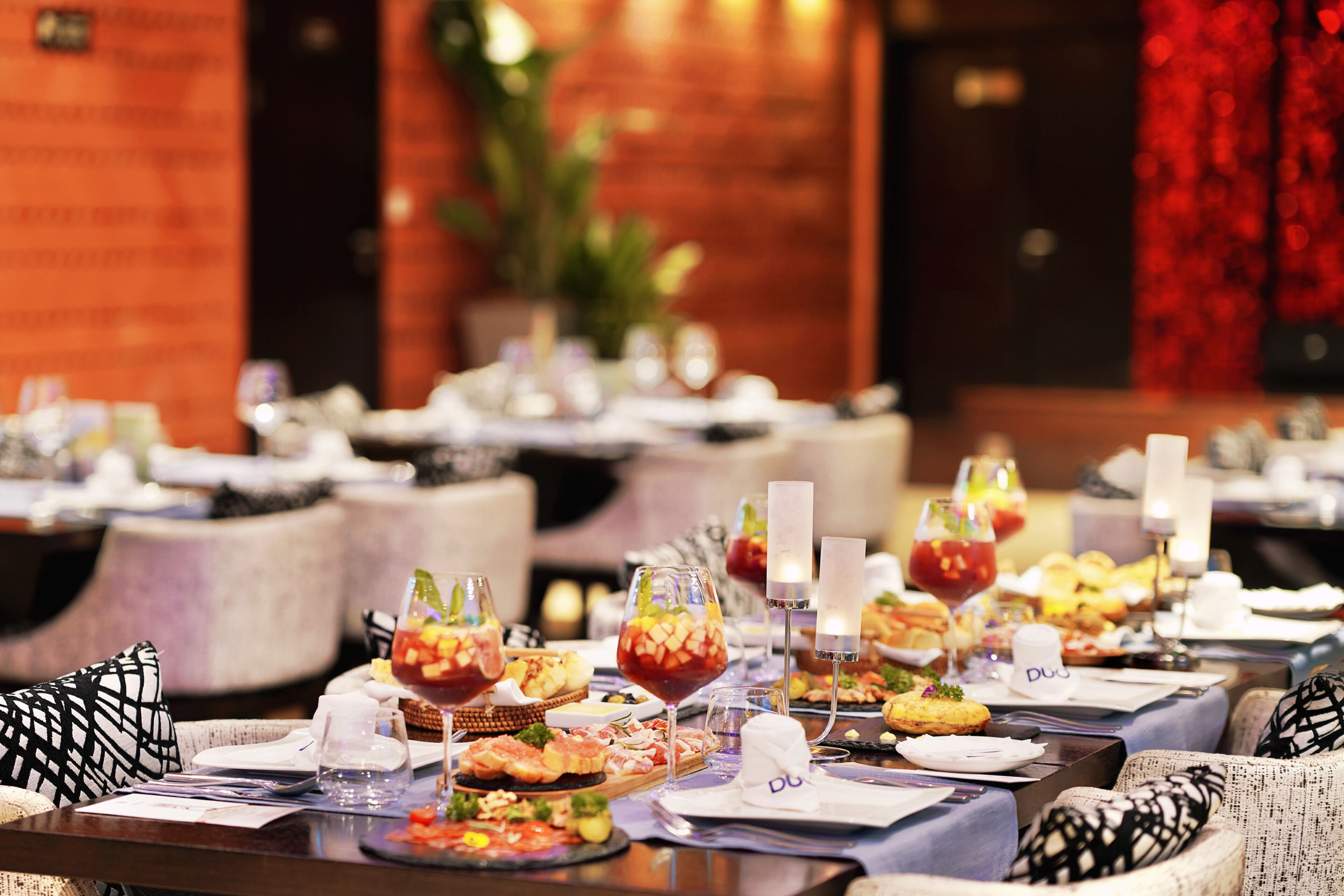 Un restaurant avec de nombreuses tables, chacune mise avec des assiettes, des verres et différents plats.