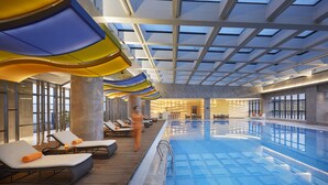 Una piscina interior con sillones de descanso y un techo con tragaluces.