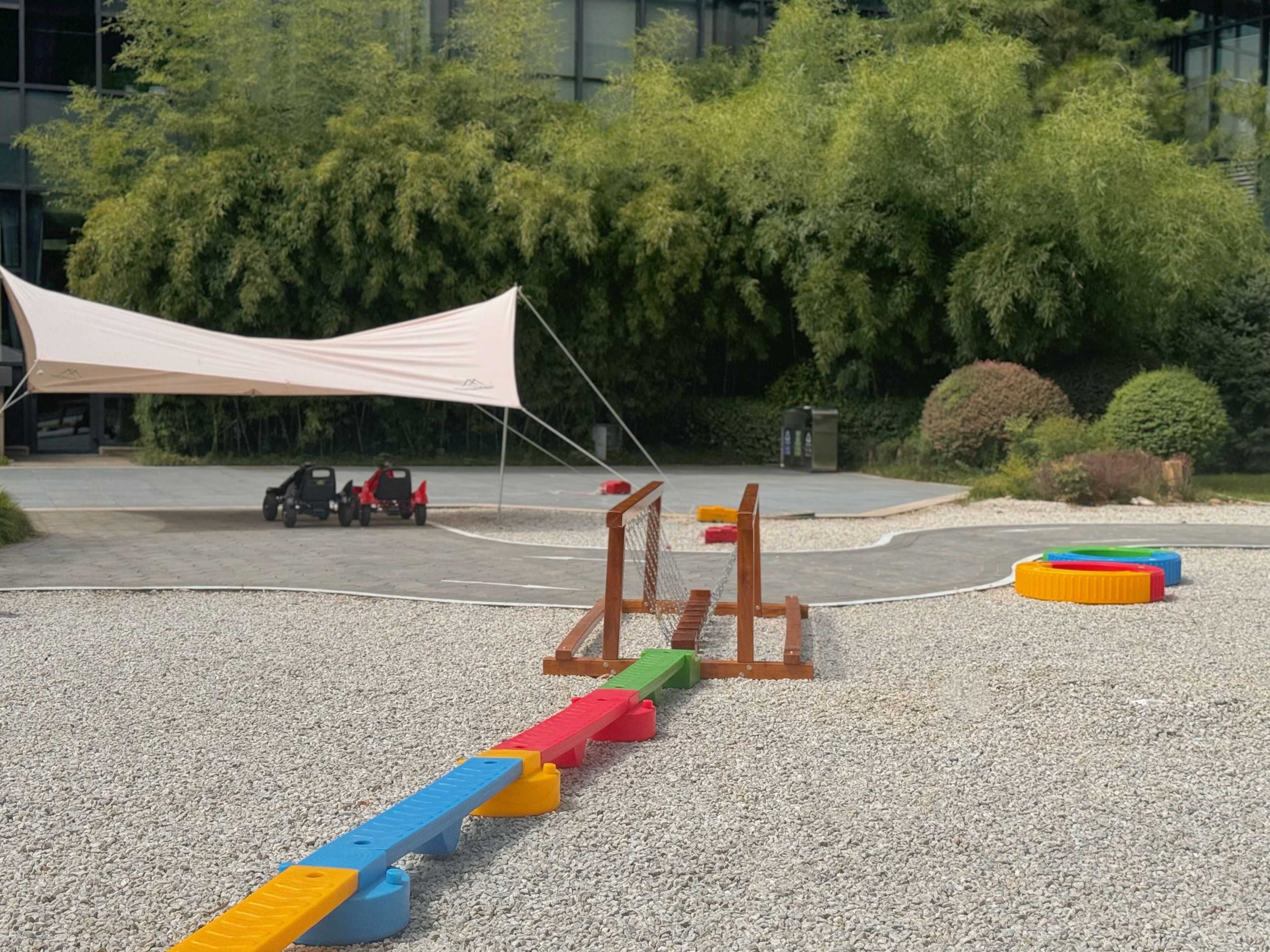 A playground with a seesaw, a climbing structure, and a tent in the background.