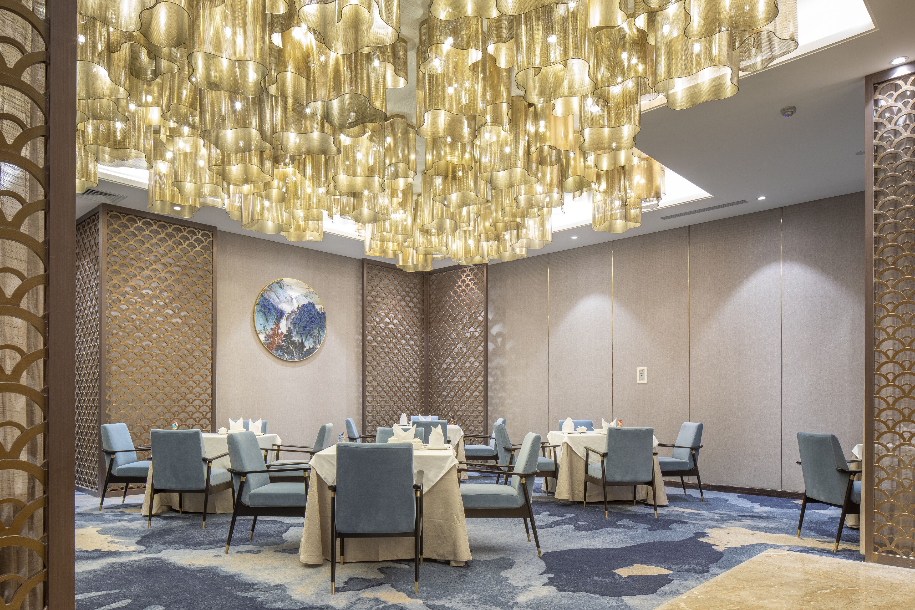 A conference room with round tables, chairs, and a decorative ceiling light fixture.