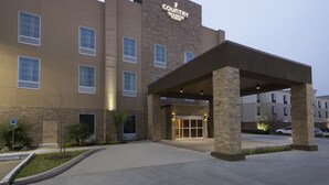A Country Inn & Suites building with a stone facade, multiple windows, and a covered entrance. - Country Inn & Suites by Radisson, Katy (Houston West), TX (Katy)