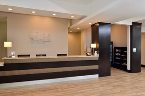 A hotel reception desk with a modern design, a reception area, and a small retail shop.