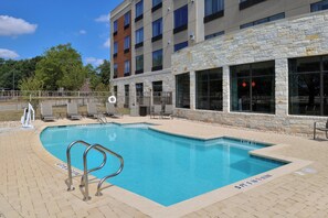 Une piscine avec une façade en pierre et un ciel d’un bleu limpide.