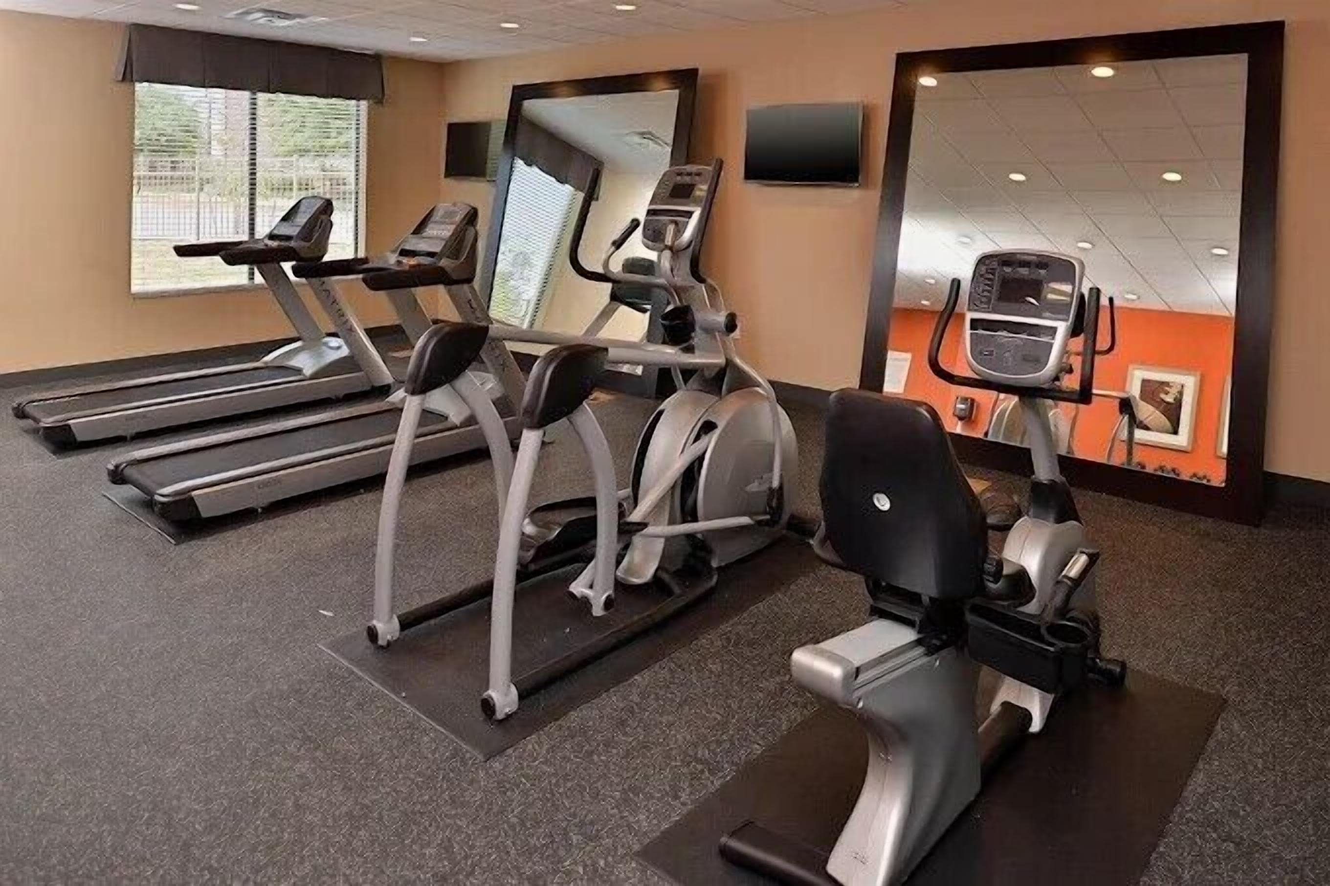 Un gimnasio con cintas de correr, elípticas y una bicicleta estática.