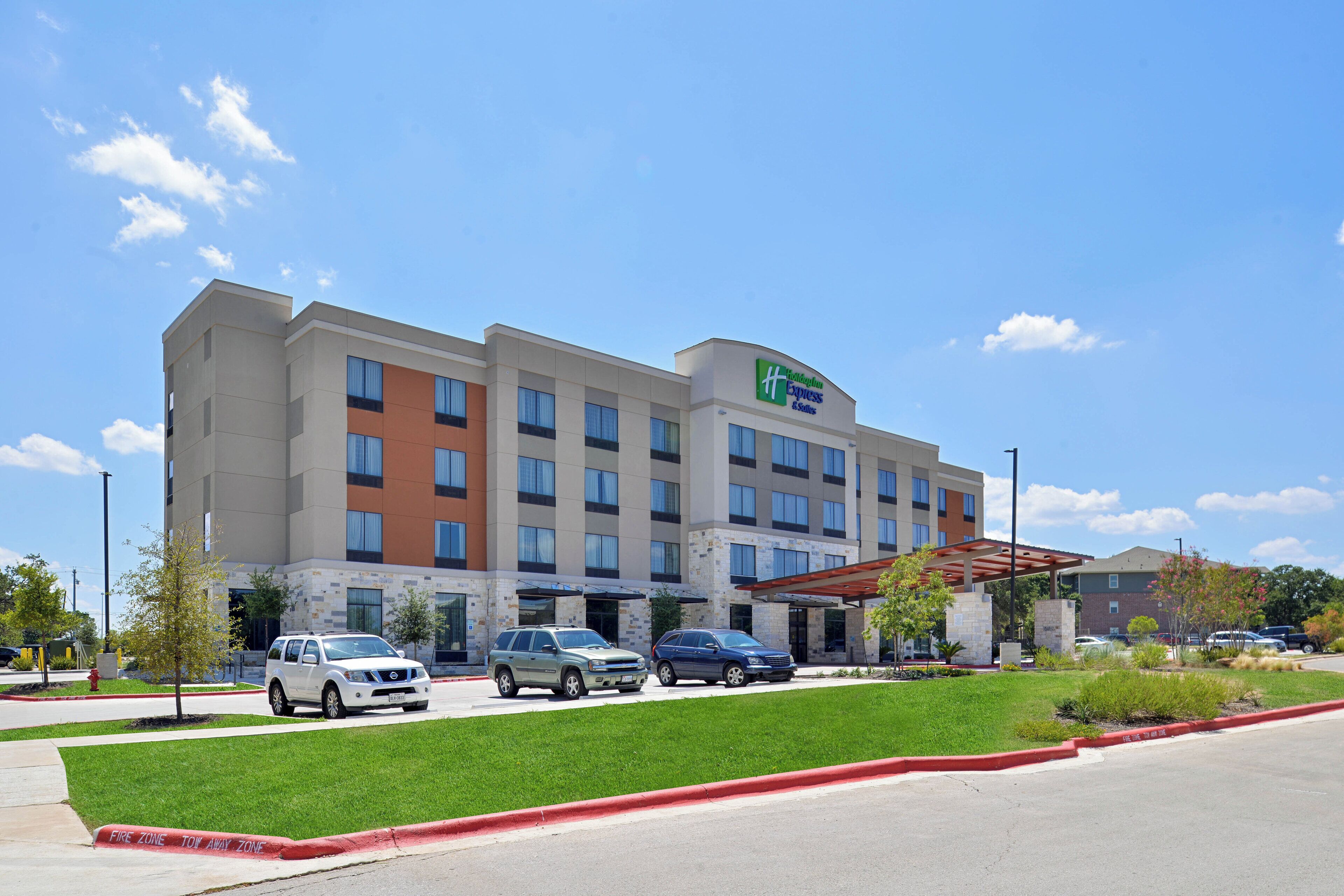 A Holiday Inn Express hotel with a parking lot, a fire lane, and a green lawn.