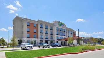 A Holiday Inn Express hotel with a parking lot, a fire lane, and a green lawn.
