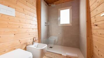 Een houten badkamer in een vakantiebungalow, met douche, toilet en wastafel.