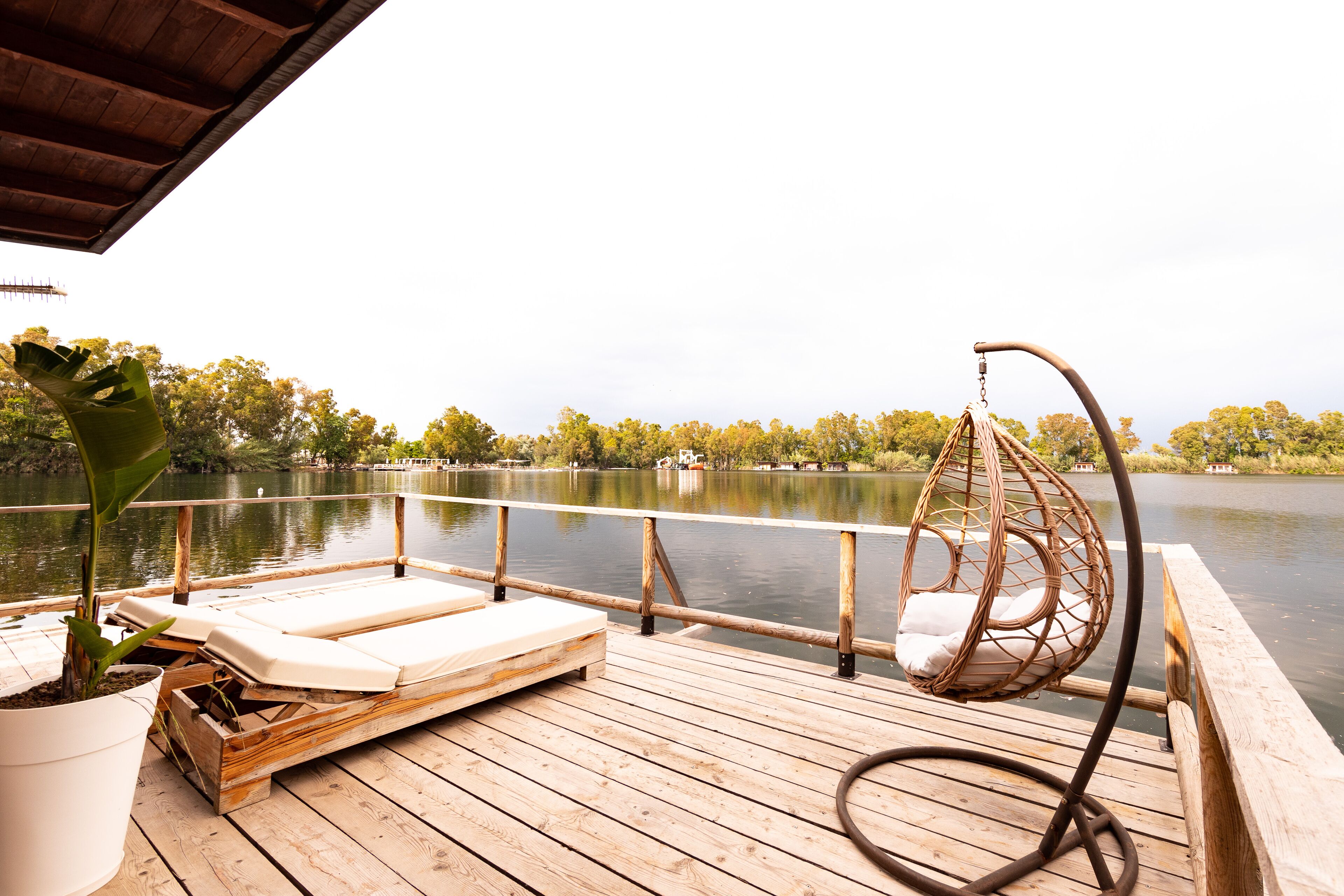 Eine Holzterrasse mit Liegestühlen und einer Hängematte mit Blick auf einen ruhigen See.